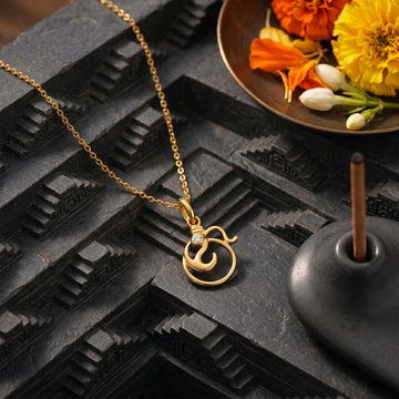 Gold necklace with a unique pendant on a textured black surface with flowers in the background