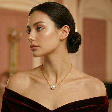 Woman wearing a burgundy off-shoulder top and pearl necklace in an elegant interior setting