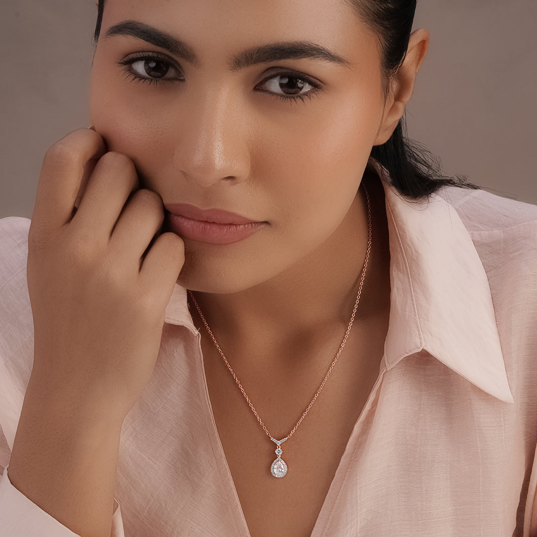 Woman wearing a necklace with a pendant against a neutral background
