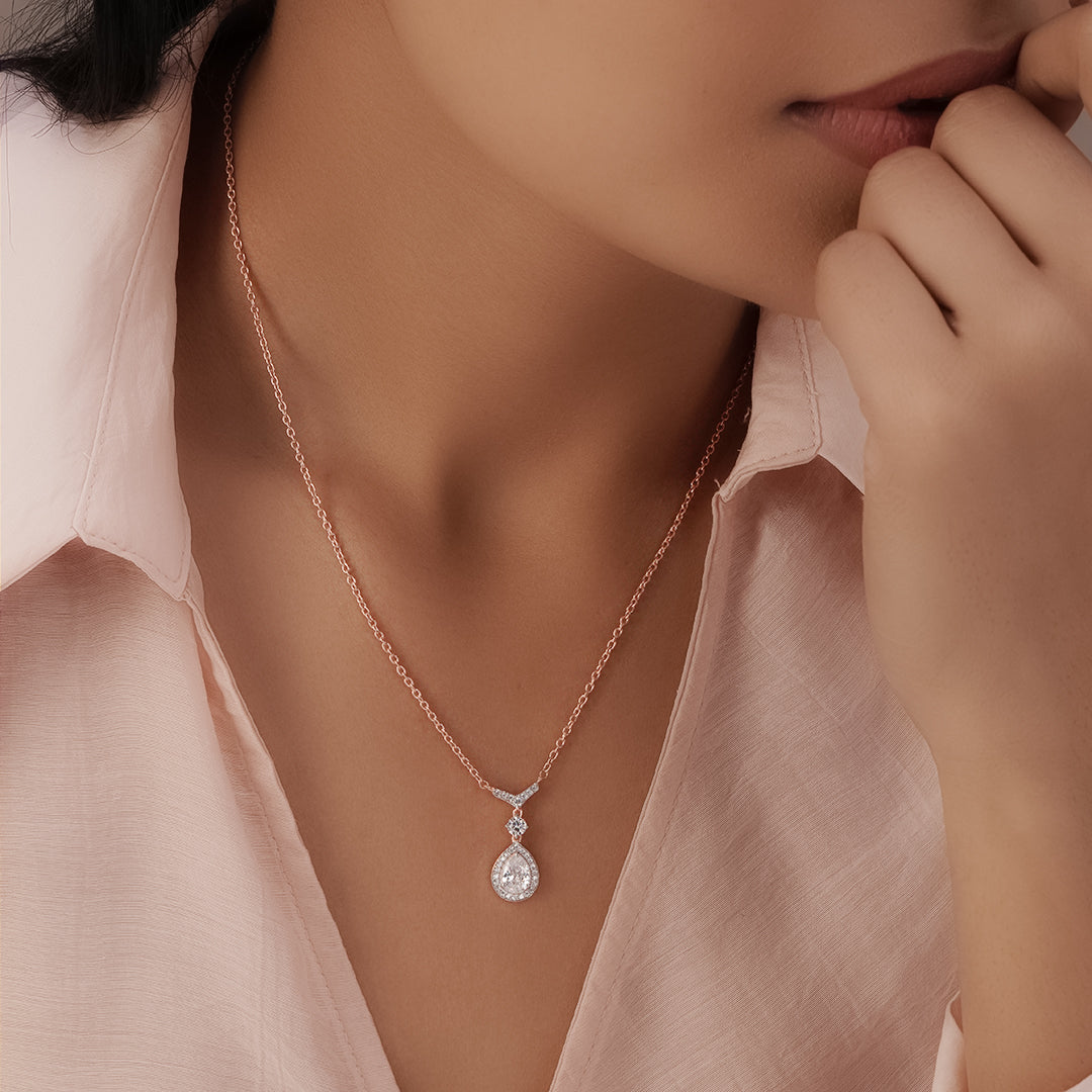 Close-up of a woman wearing a rose gold necklace with a diamond pendant.
